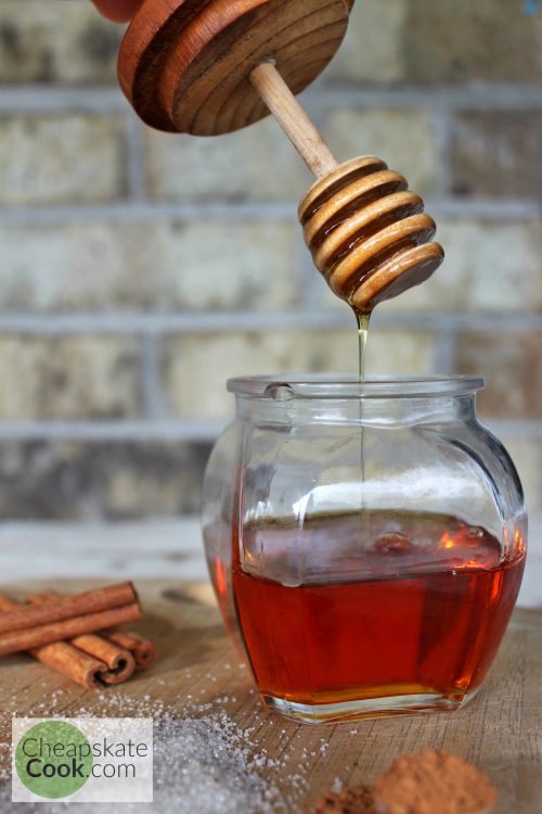 A golden drizzle of honey falling into a glass bowl