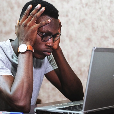 man looking at computer screen and holding his head