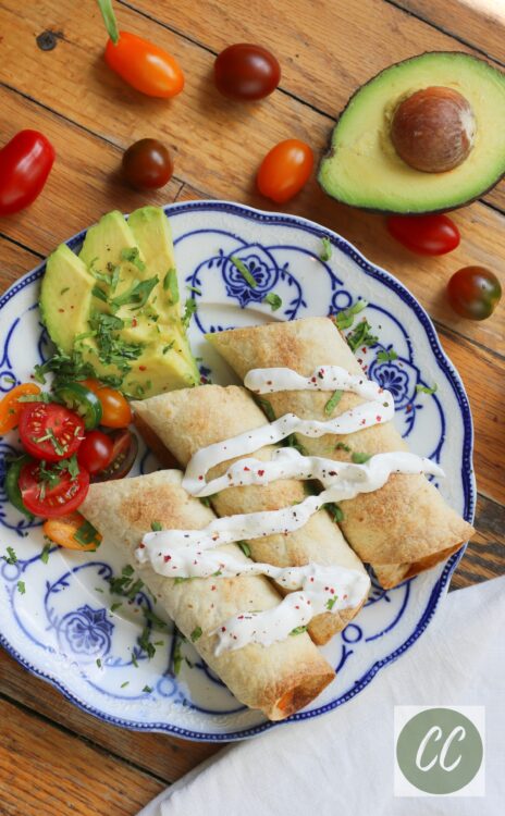 homemade taquitos on a plate with veggies